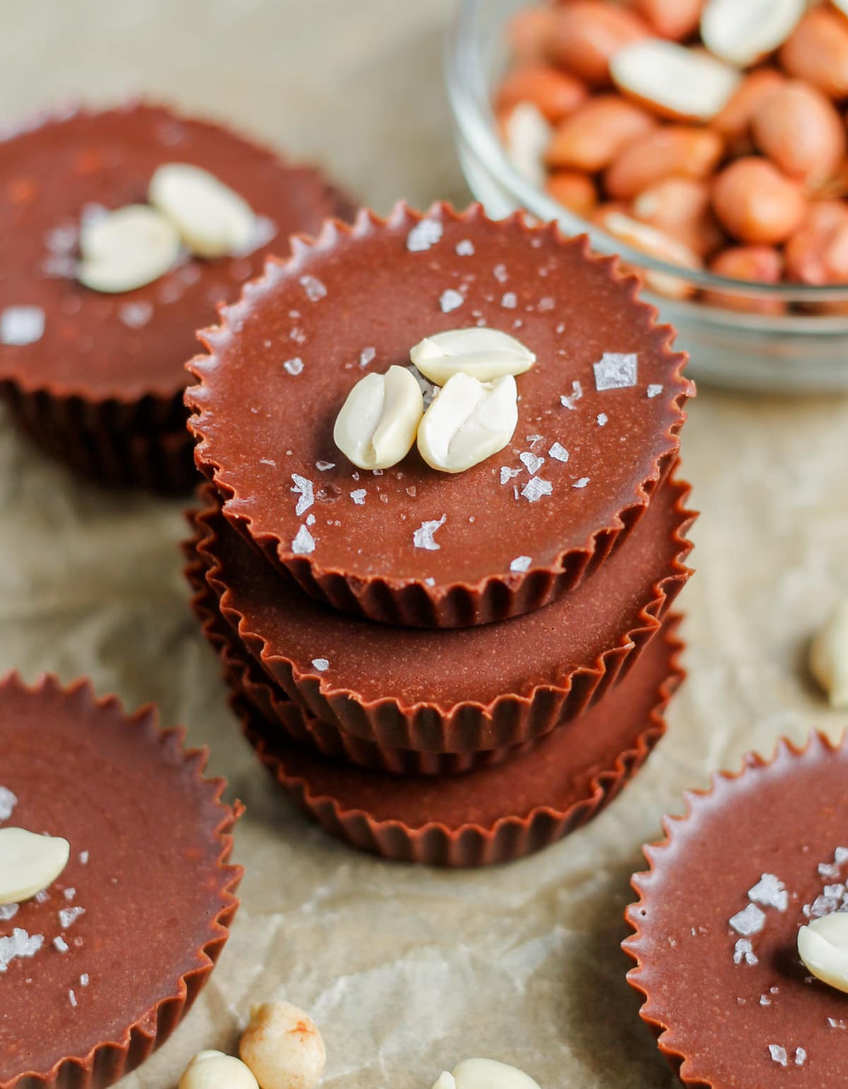 A stack of healthy peanut butter cups topped with chopped peanuts and flaked sea salt.