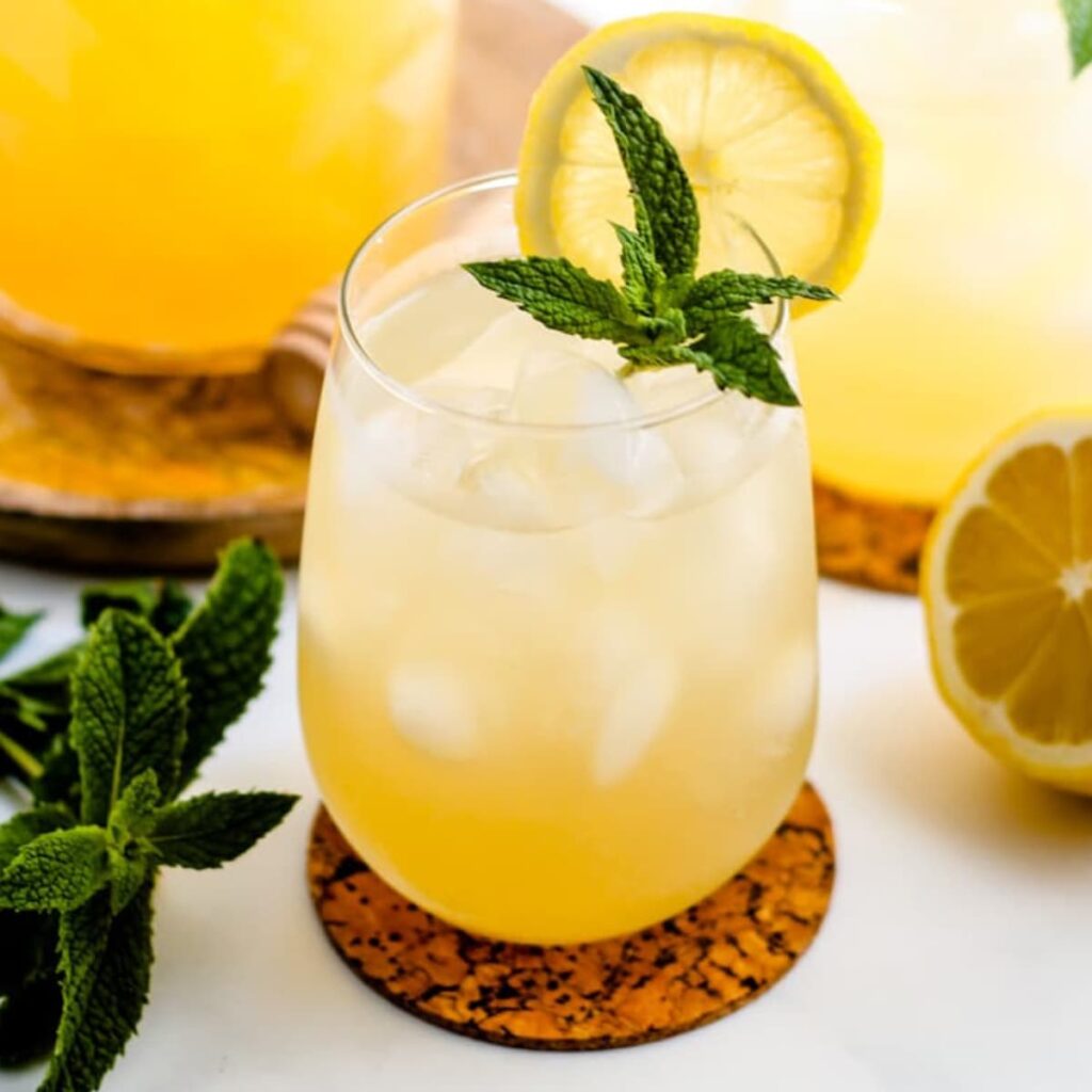 A glass of iced green tea garnished with lemon and mint.