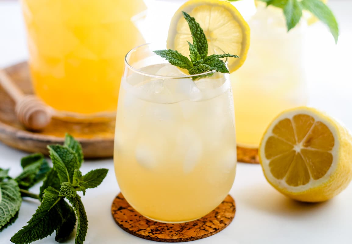A glass of iced green tea garnished with fresh mint and lemon slices.