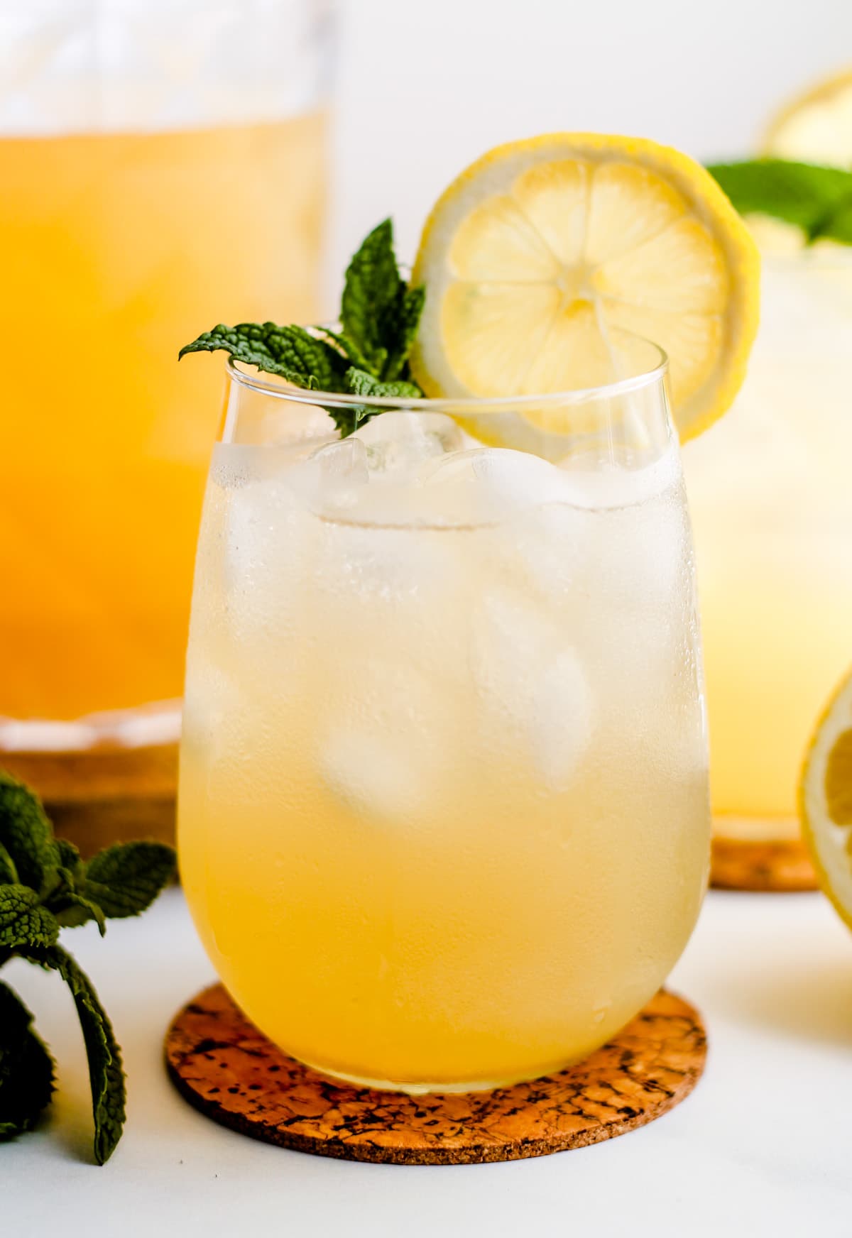 A glass of iced green tea garnished with lemon and mint.