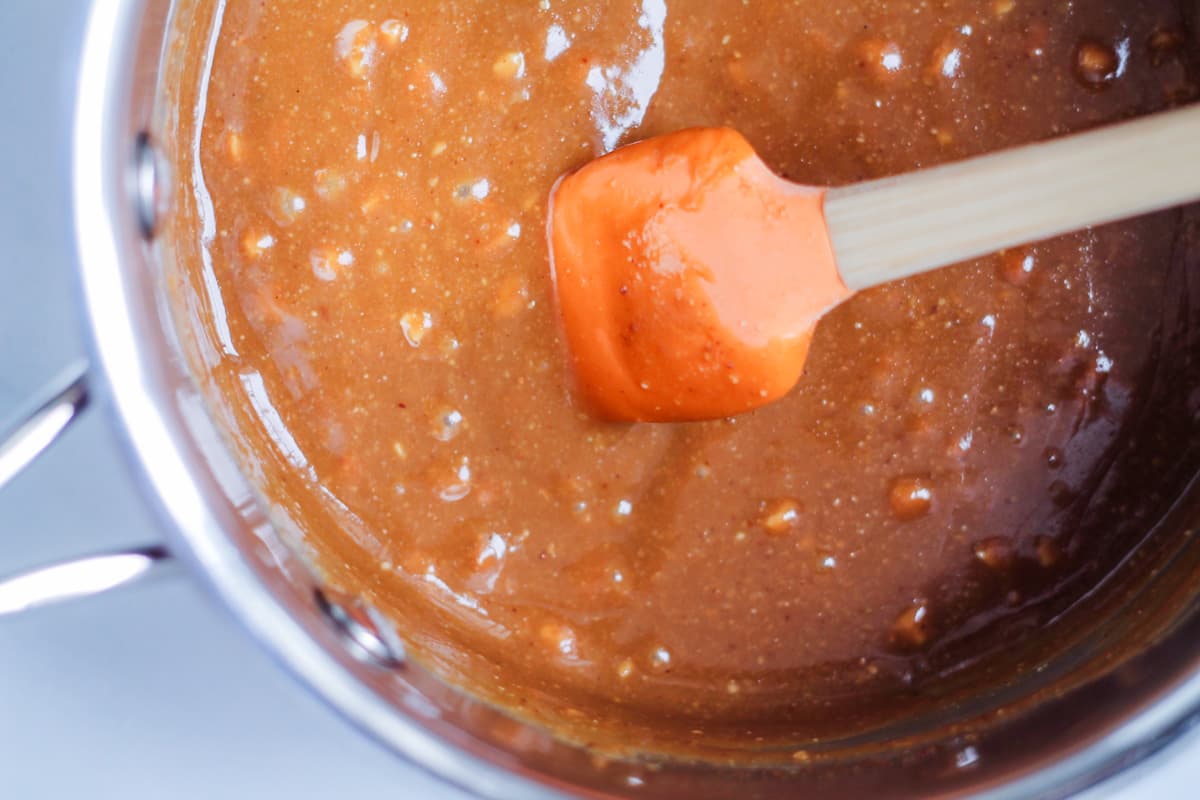 A spatula stirring a mixture in a small saucepan.
