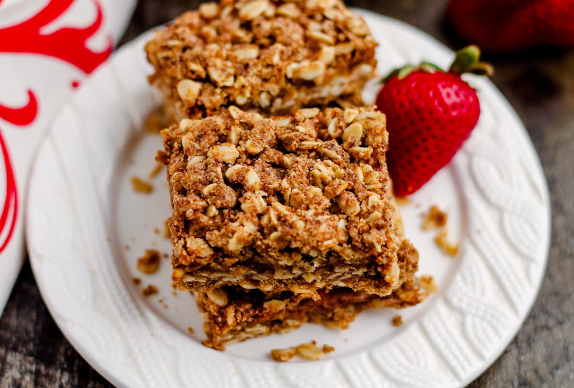 a plate of strawberry crumble bars withfresh strawberries.