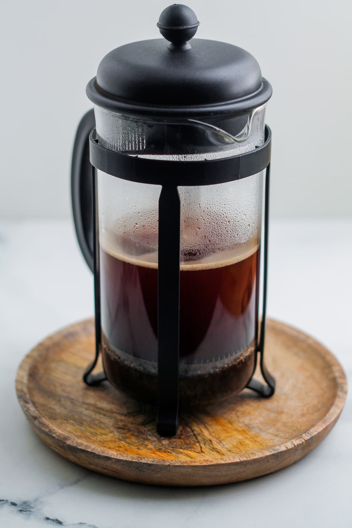 A french press with coffee brewing inside it.