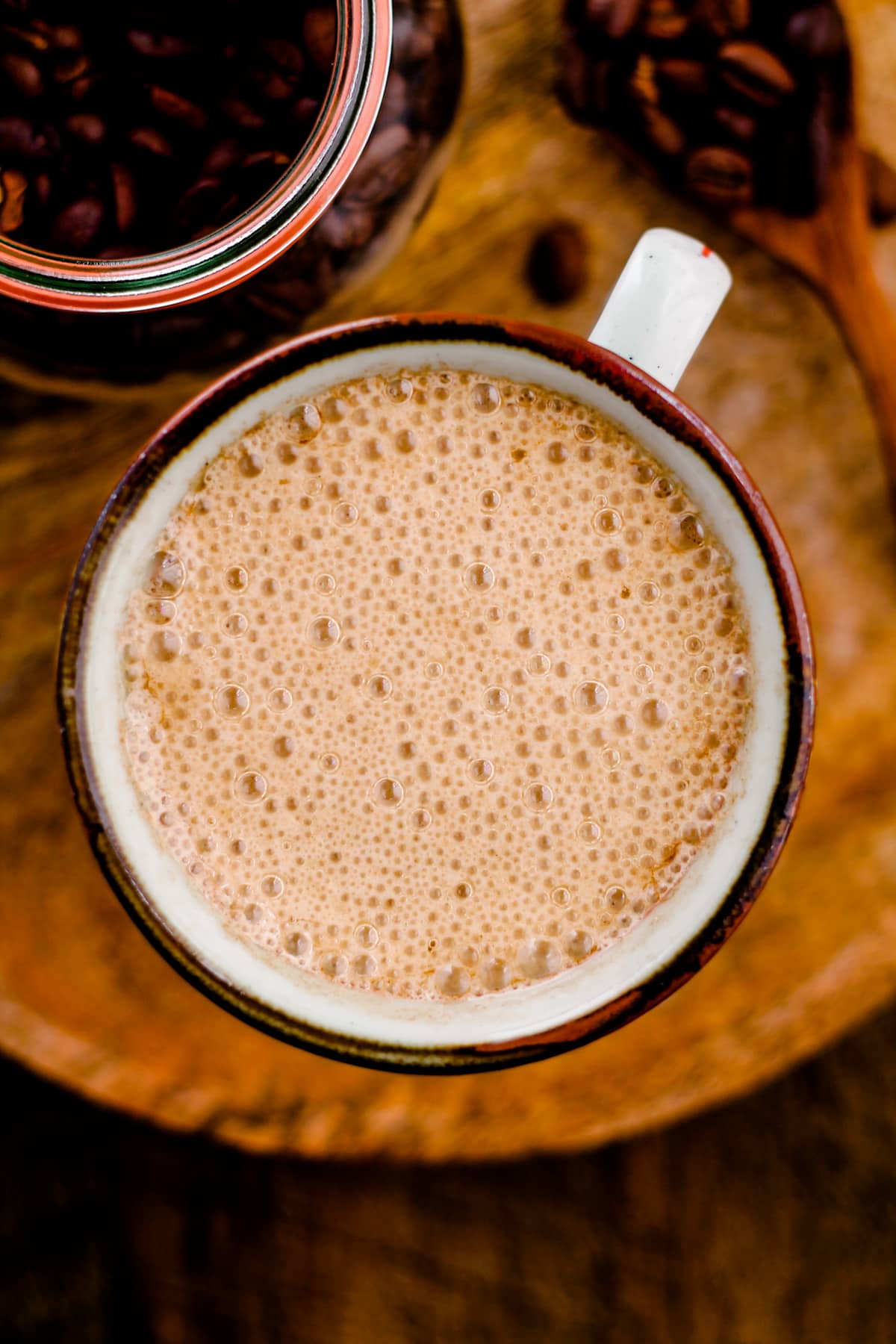 A mug filled with creamy Vegan Bulletproof Coffee on a wooden serving tray.