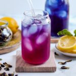 A glass of butterfly pea tea on a coaster.