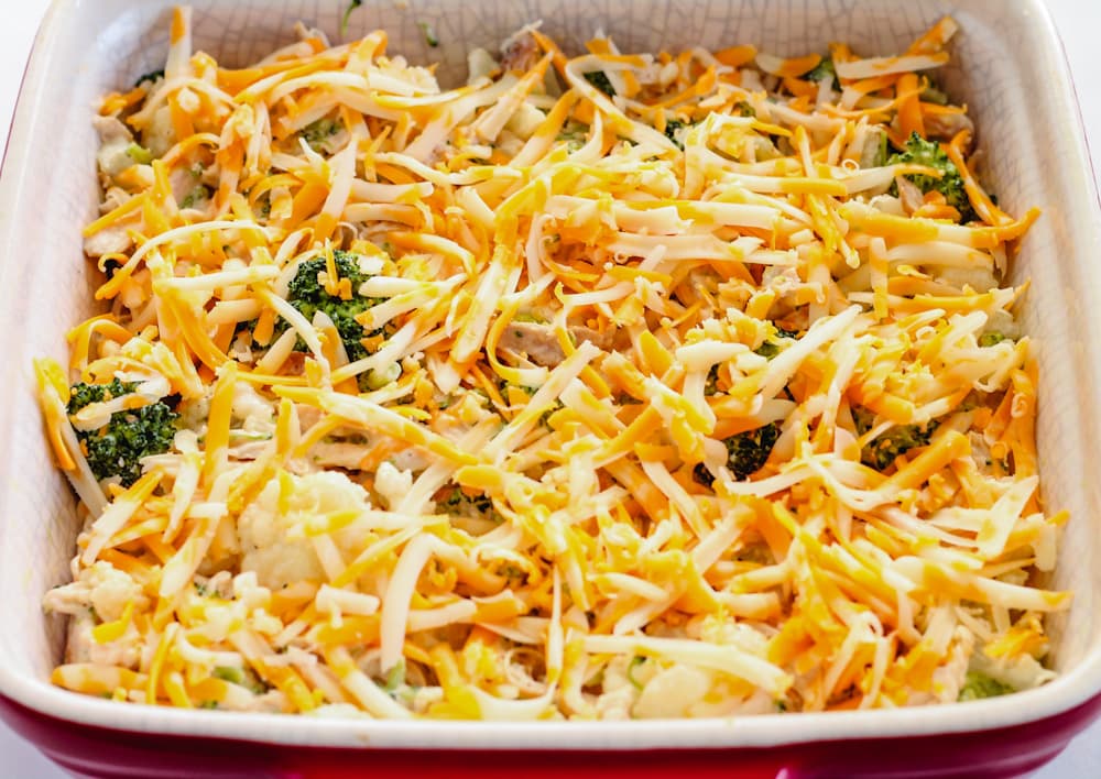 A baking dish with a meal covered in shredded cheese in it.