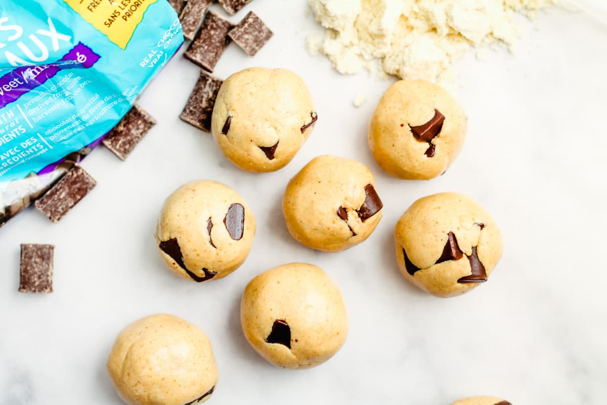 Cookie dough protein balls spread out on a counter.