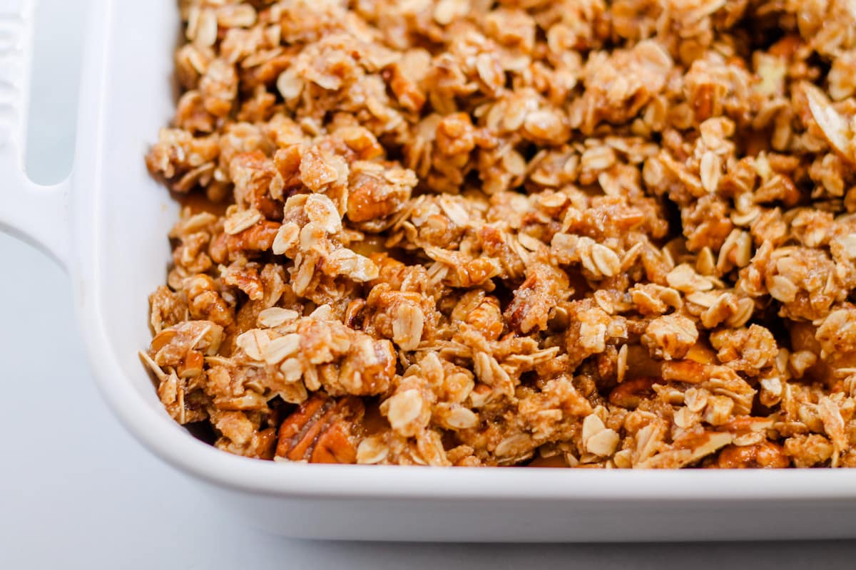 Crumble topping spread evenly over peaches in a baking dish.