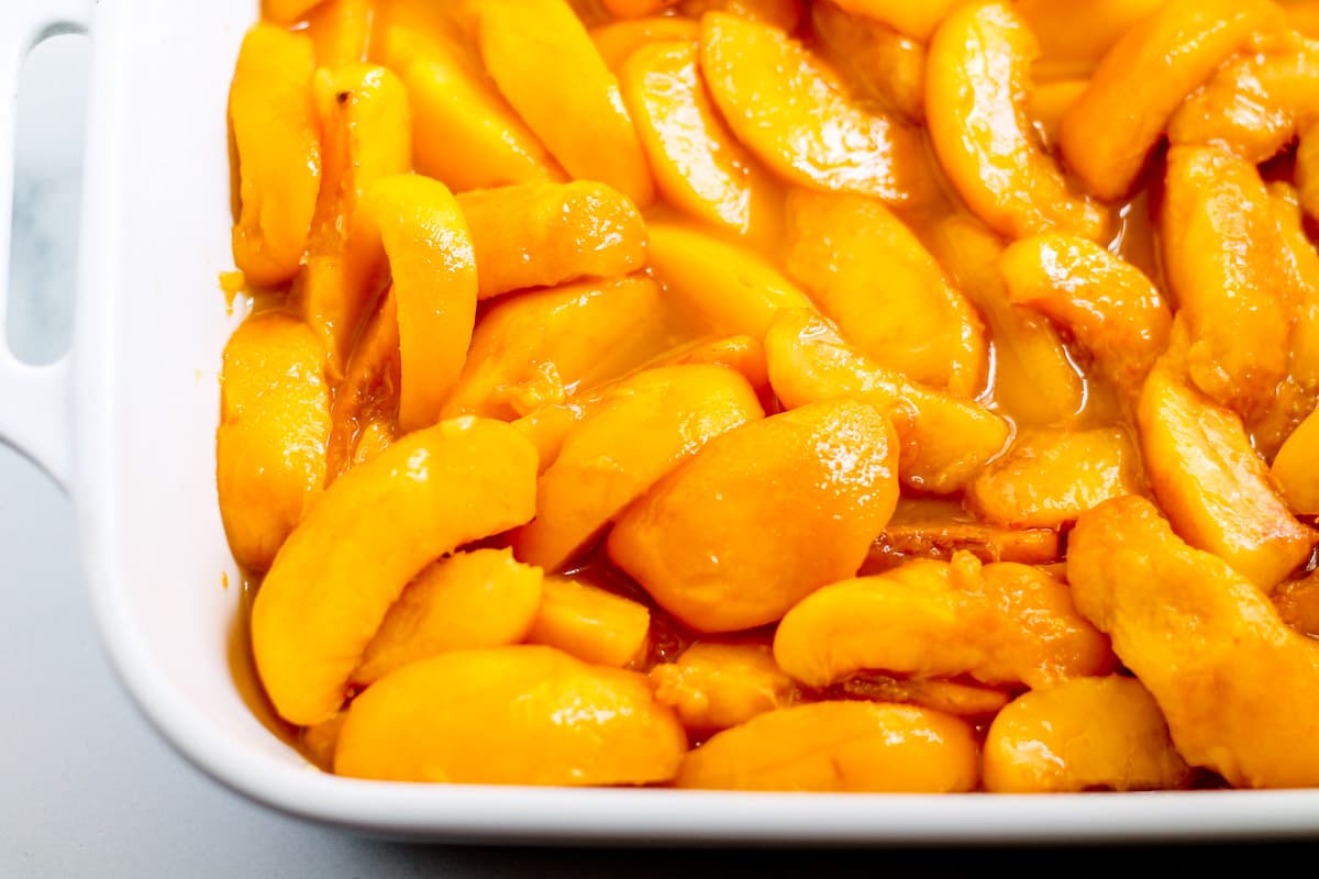 Sliced peaches in a baking dish.
