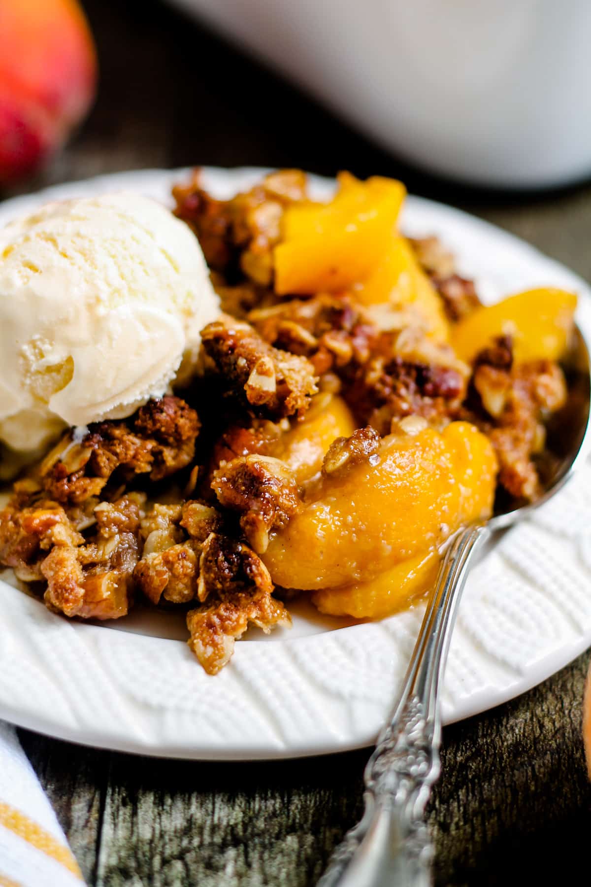 A plate of peach crisp topped with ice cream.
