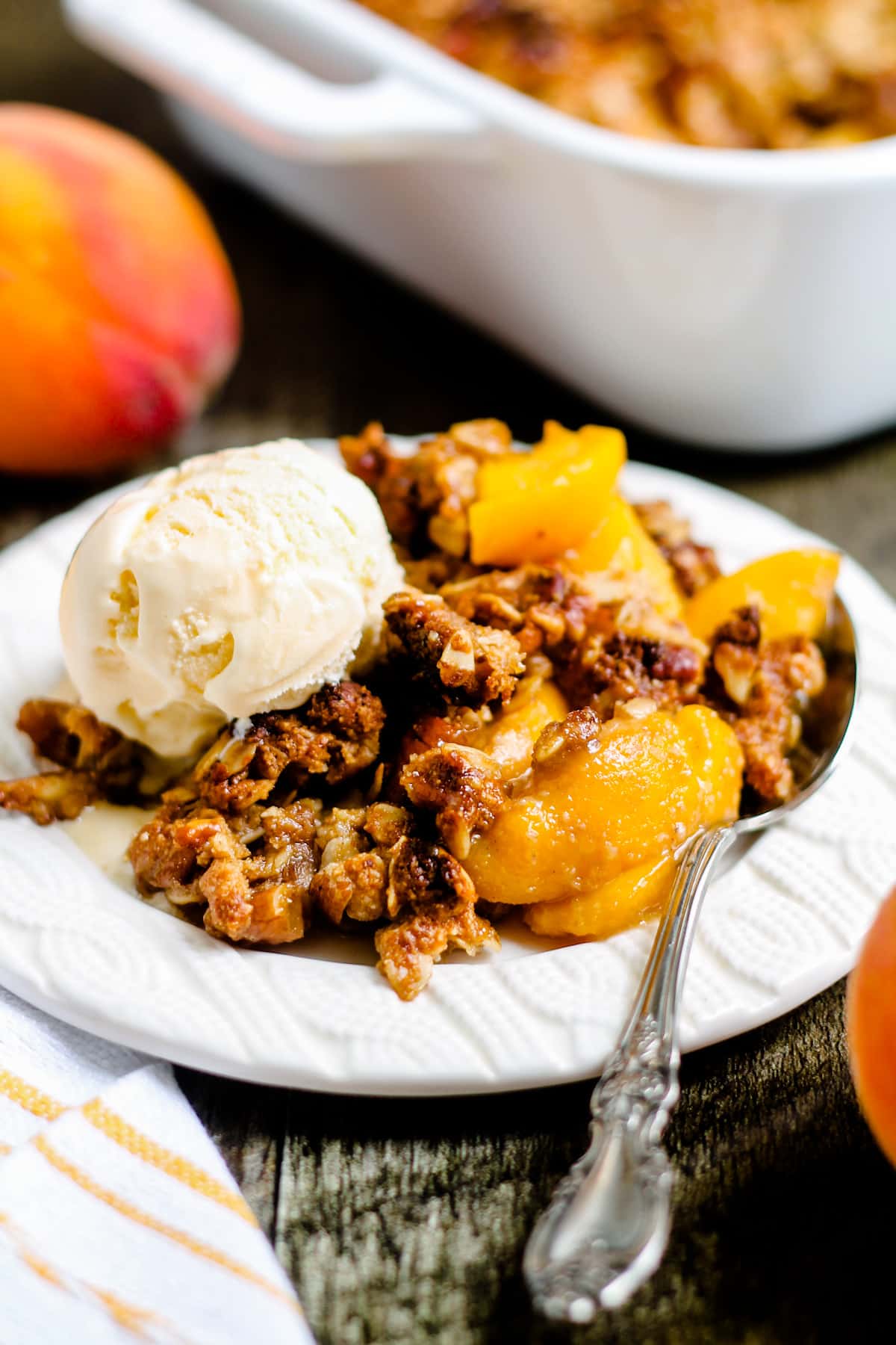 A plate of freshly baked peach crisp topped with ice cream.