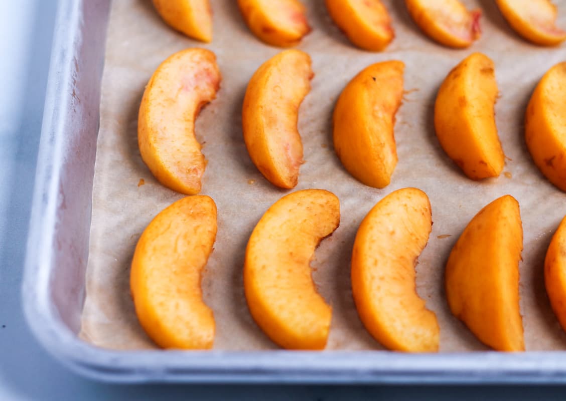 Frozen peach slices on a baking sheet.