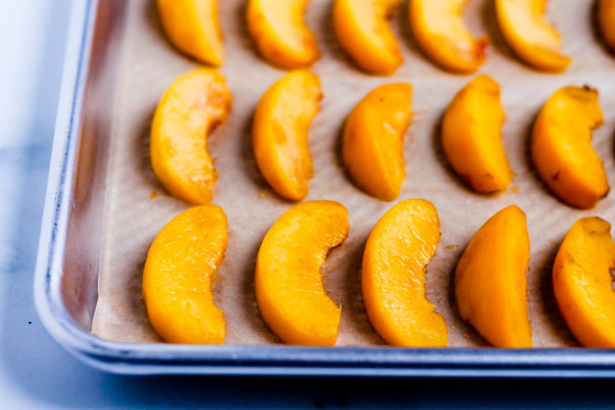 Fresh peach slices on a baking sheet.