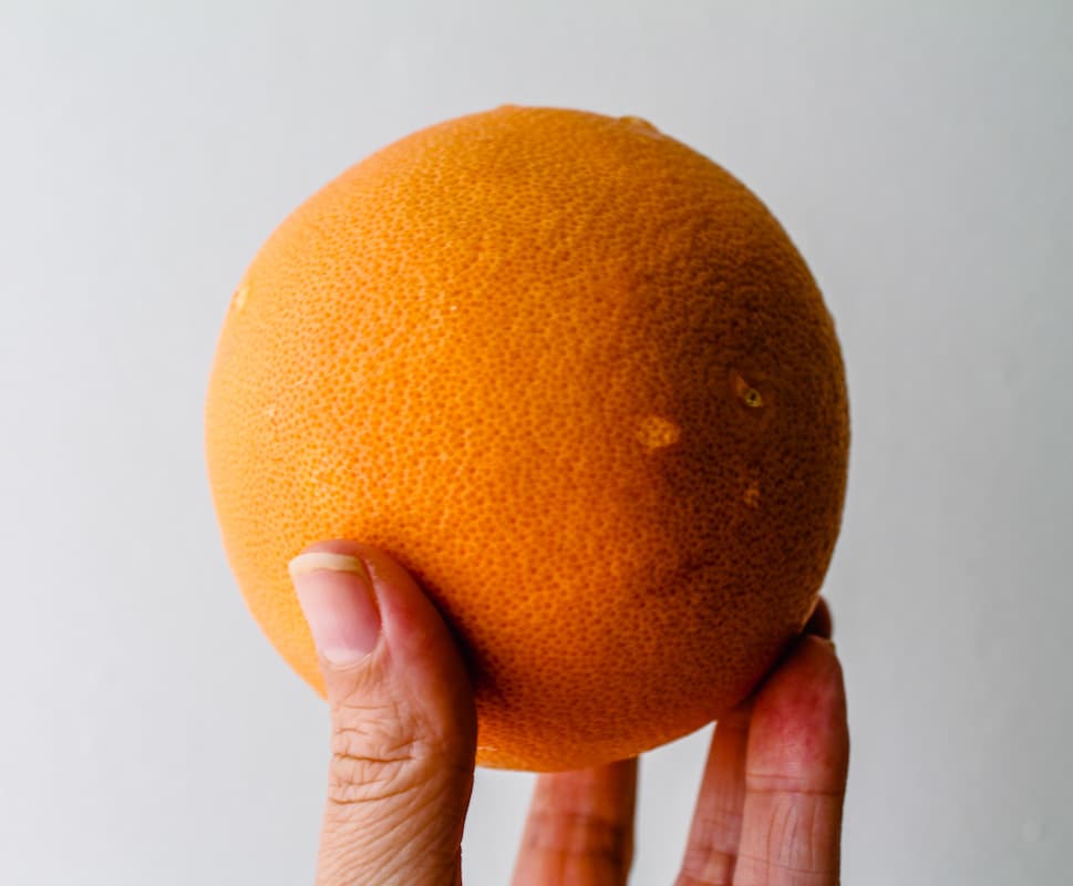 A hand holding an orange.