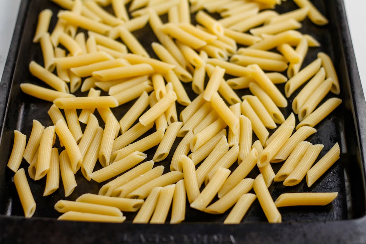 Cooked noodles cooling on a baking sheet.