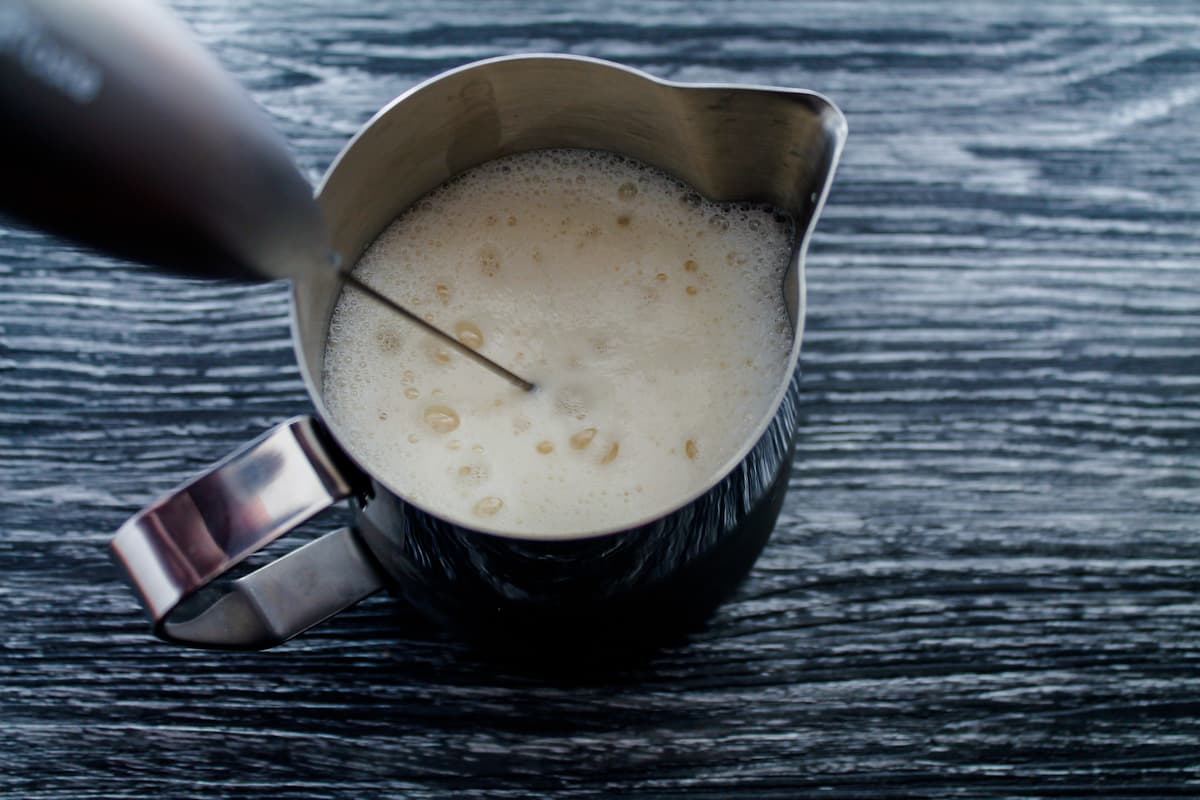 Milk being frothed in a pitcher.