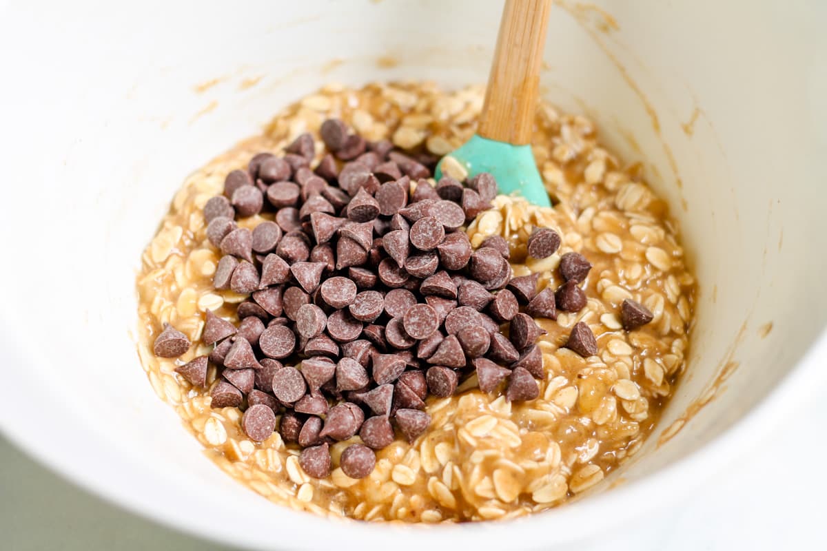 Chocolate chips being added to a mixture in a bowl.