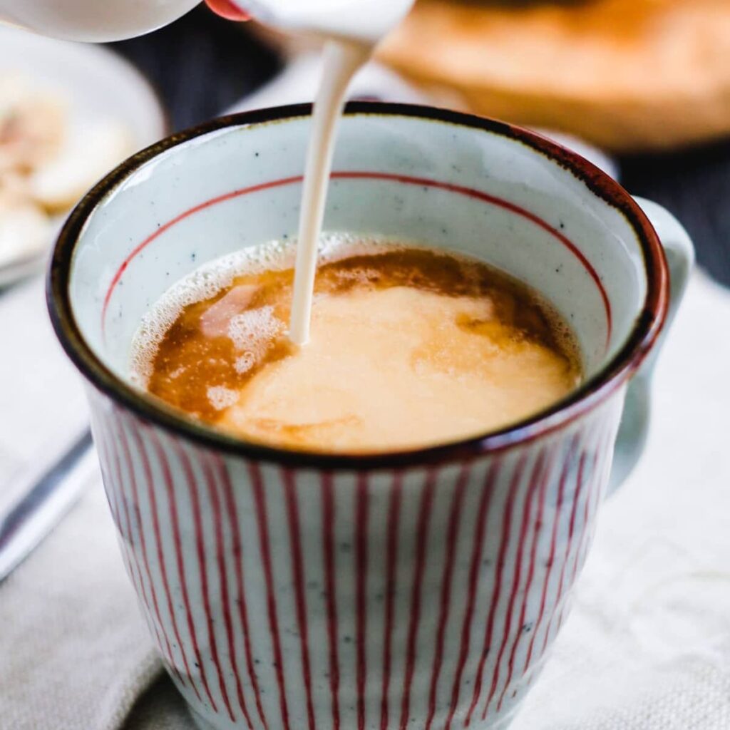 Cashew Coffee Creamer being poured into a cup of coffee.