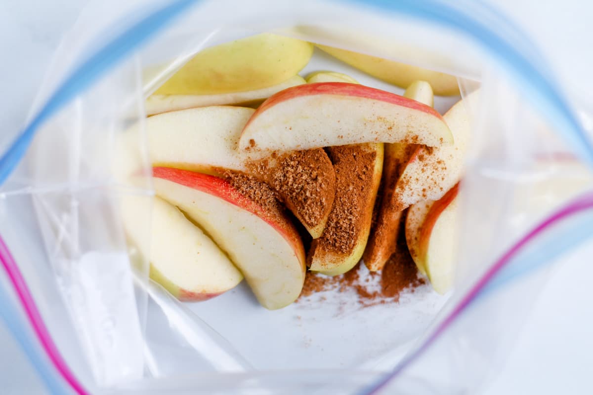 Cinnamon and coconut sugar sprinkled on fruit slices in a ziploc bag.