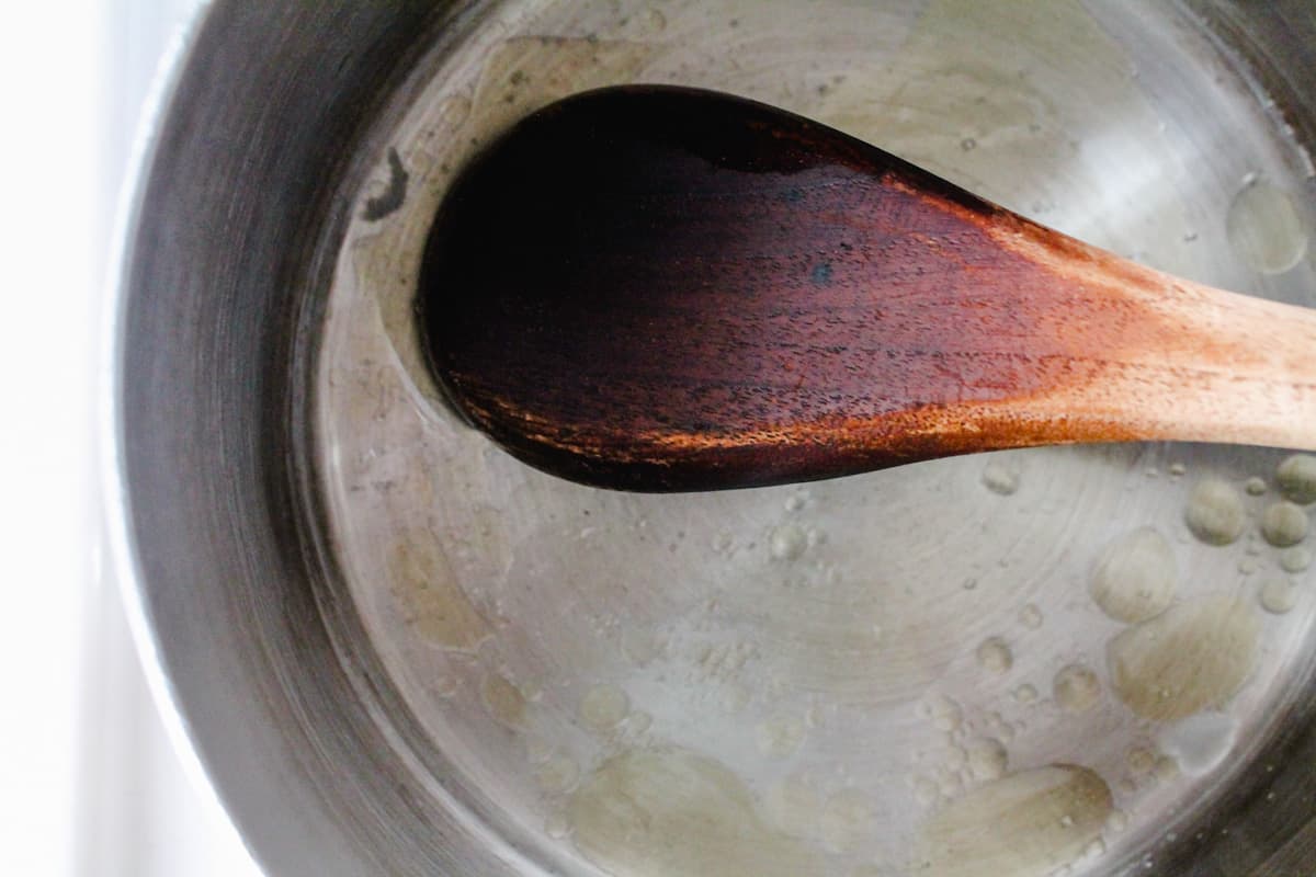 A spoon stirring ingredients in a small saucepan.