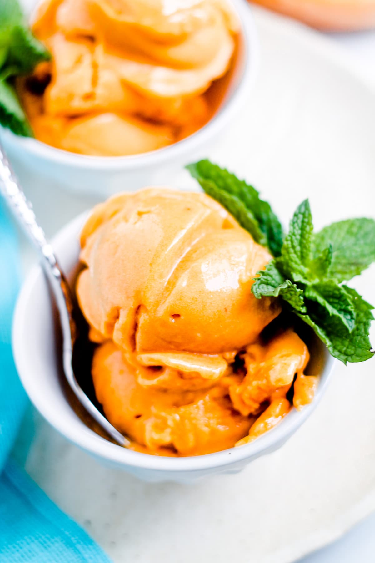 A spoon in a bowl of peach sorbet.