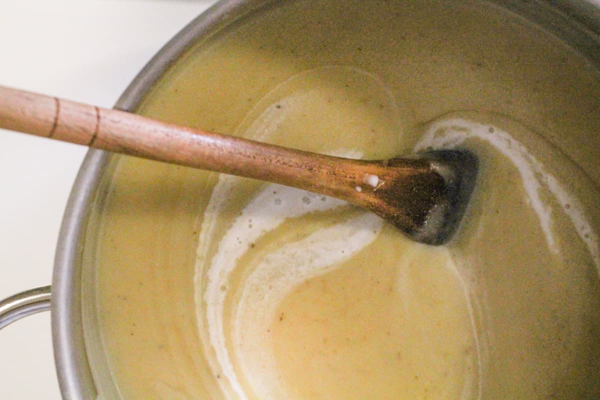A wooden spoon stirring a pot of soup.