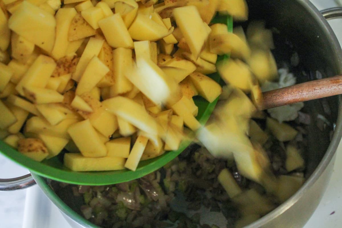 Chopped potatoes being poured into a large pot.
