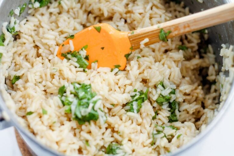 Cilantro lime mixture being stirred into a pot of warm rice.