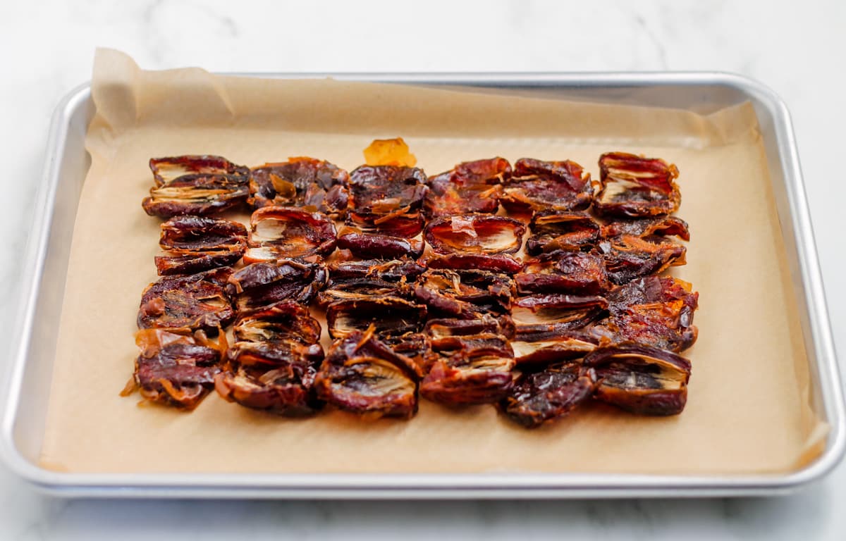 Dates opened up and layered on a baking tray.