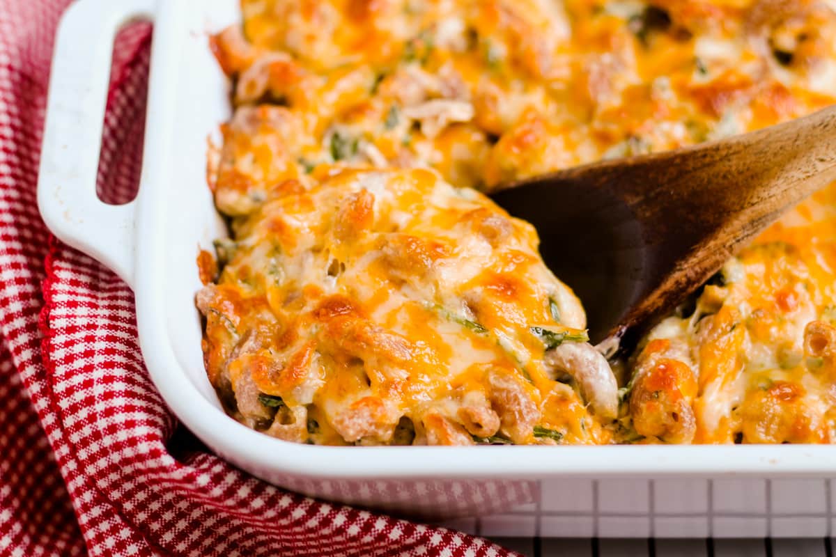 A spoon serving healthy tuna casserole from a baking dish.