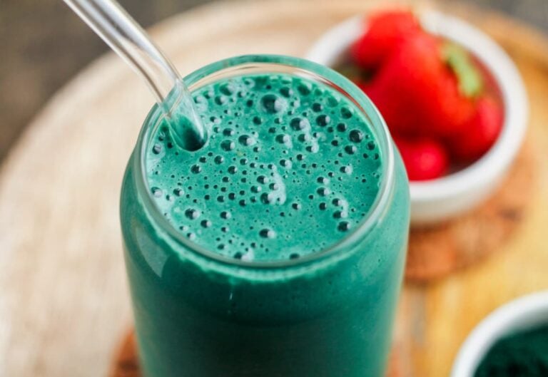 A spirulina smoothie in a glass with a straw.