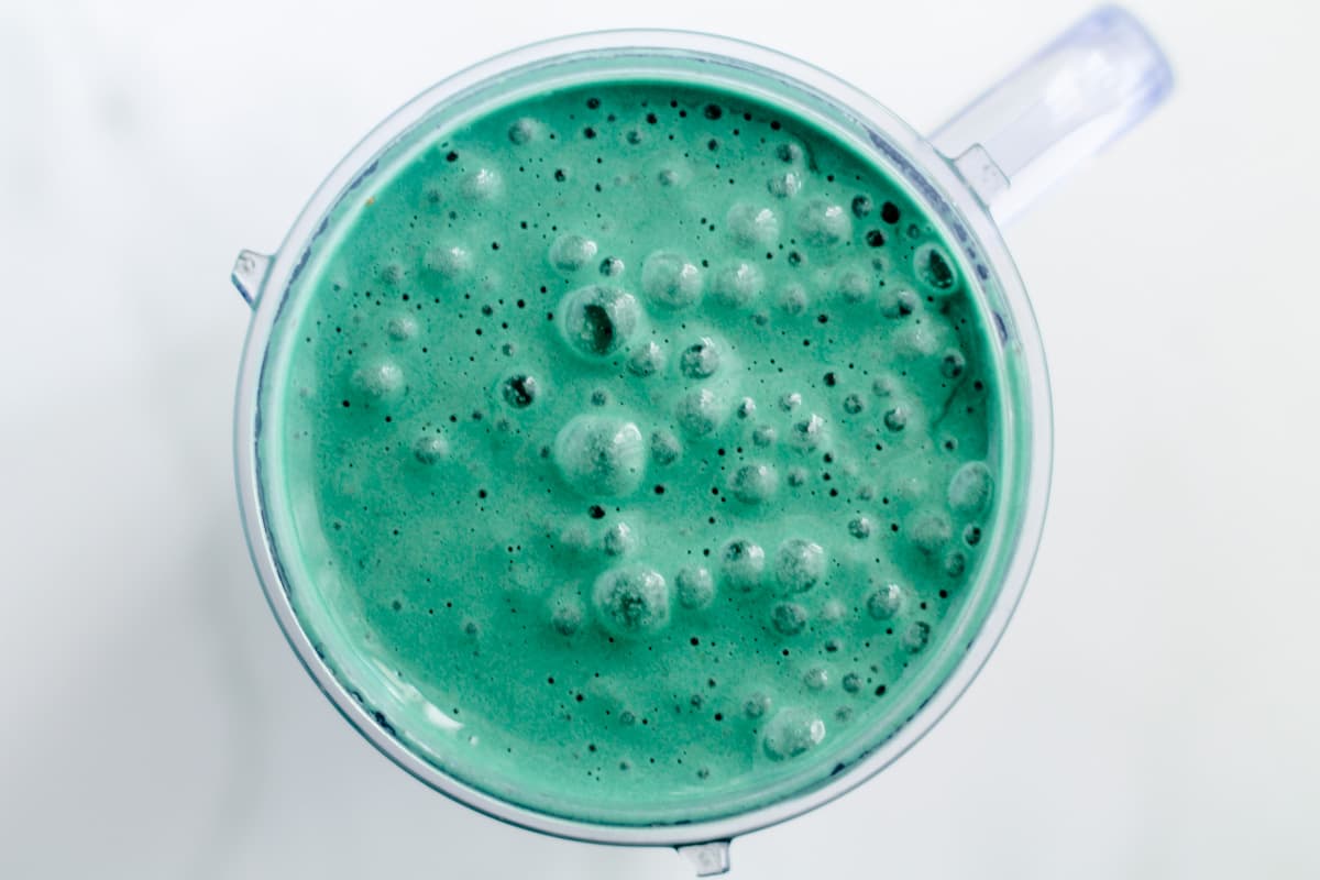 A frothy green liquid in a blender cup.