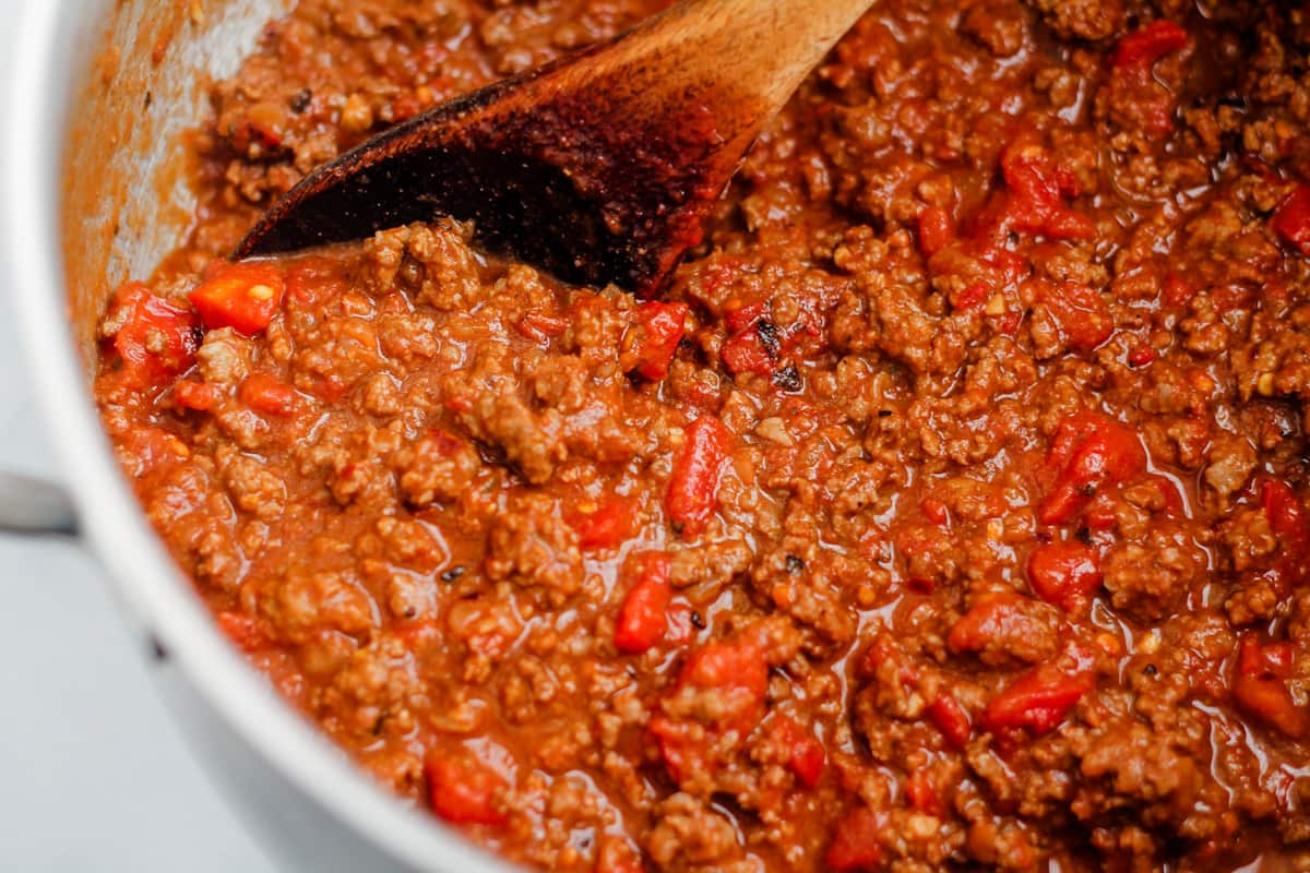 Tomato and beef mixture simmering on the stove in a large pot.