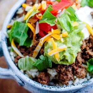 A taco rice bowl topped with salsa, sour cream and guacamole.