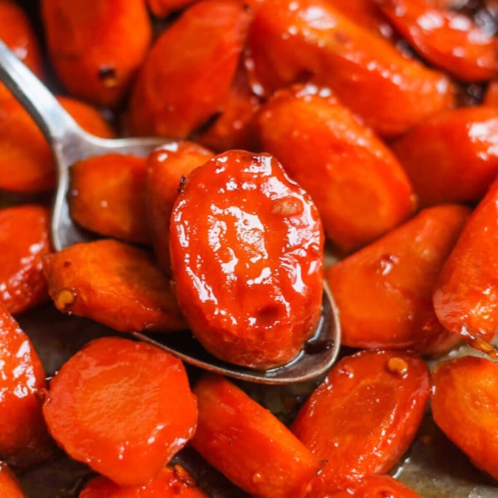 A spoon scooping a portion of maple roasted carrots.