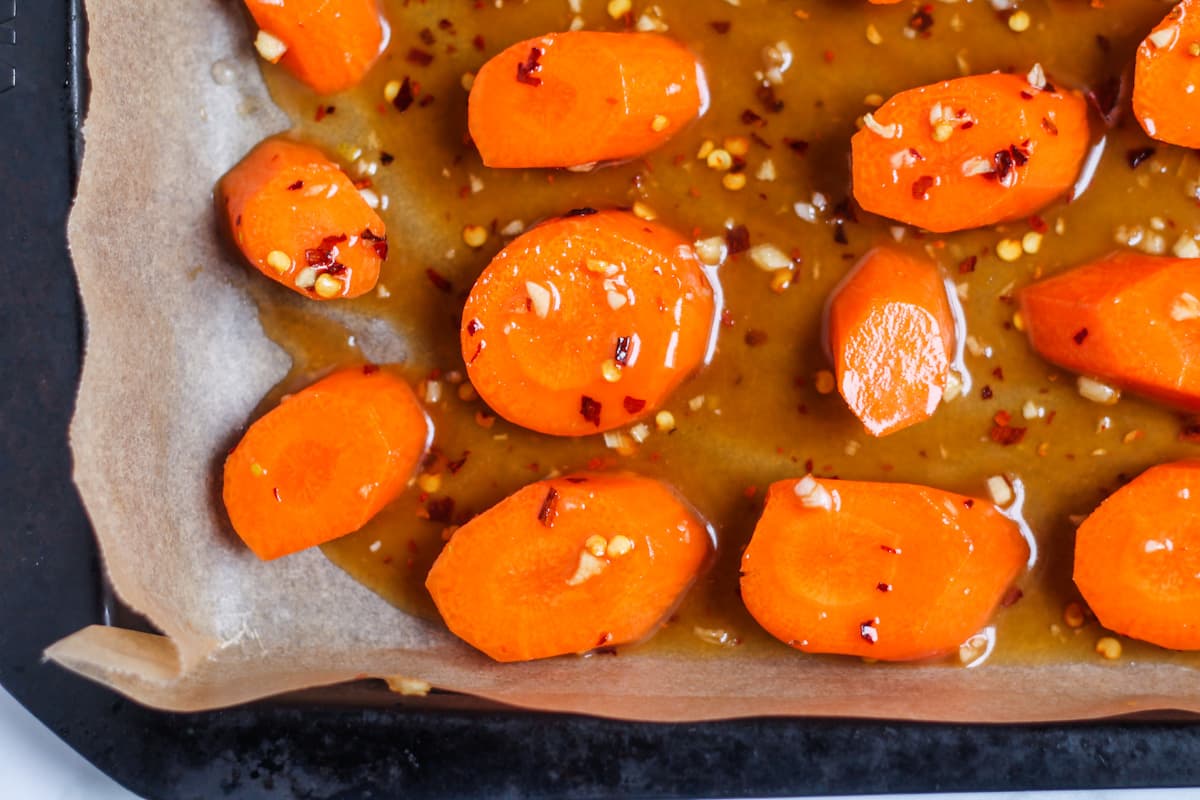 Carrots on a baking sheet with maple glaze poured over top.