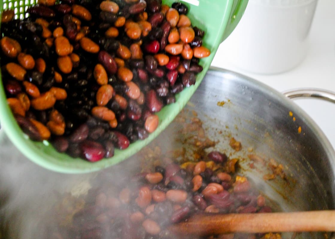 Beans being poured into a large saucepan.