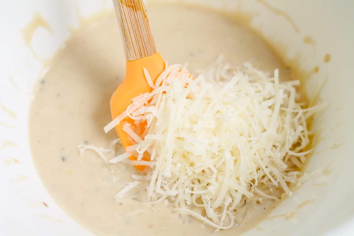 Parmesan cheese being added to a bowl of ingredients.