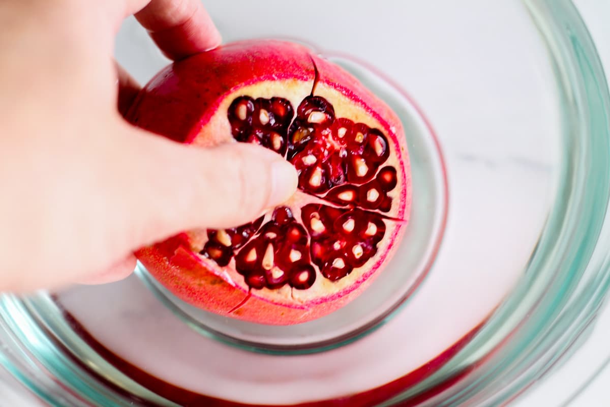 A hand breaking into a pomegranate.