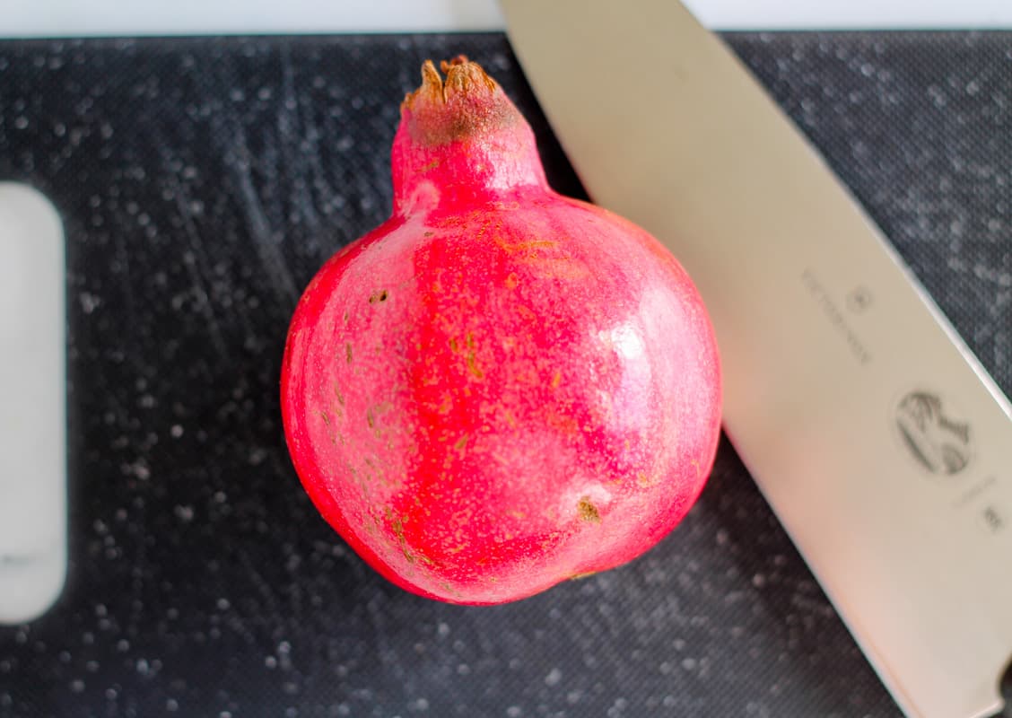 A pomegranate on a cutting board.
