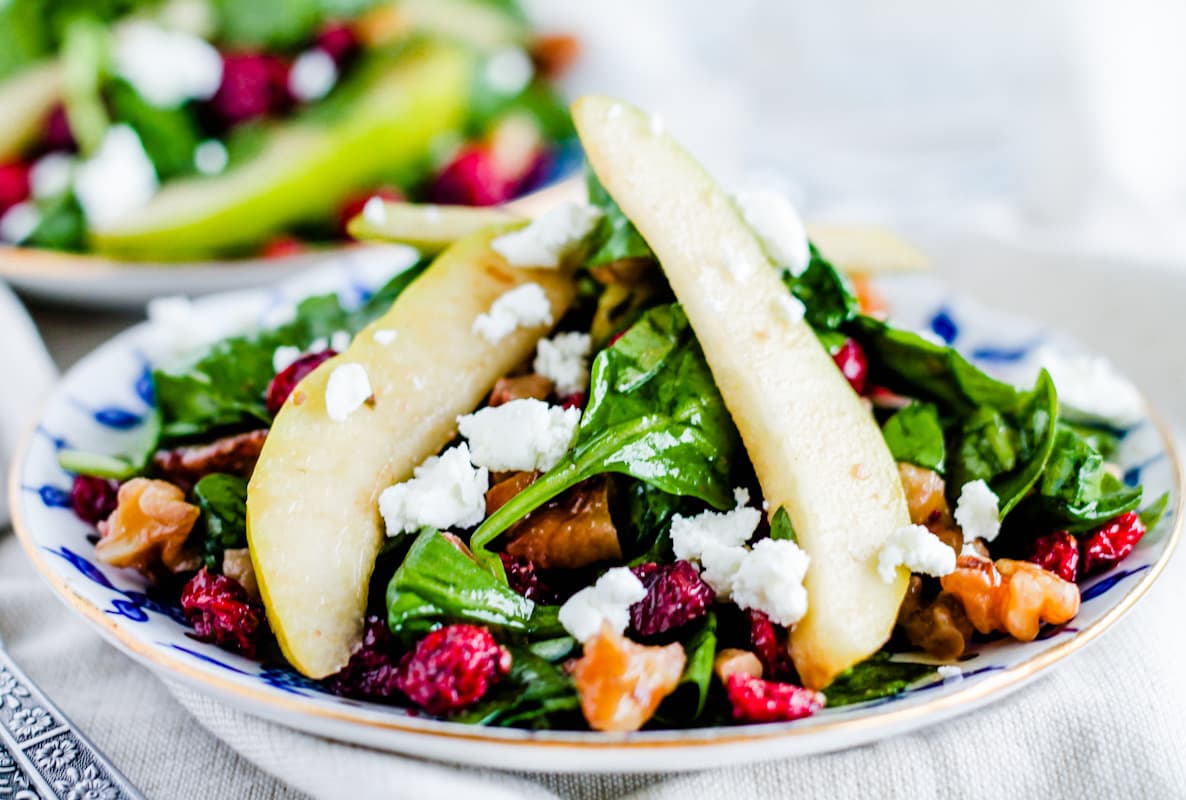 A spinach cranberry salad on a plate.