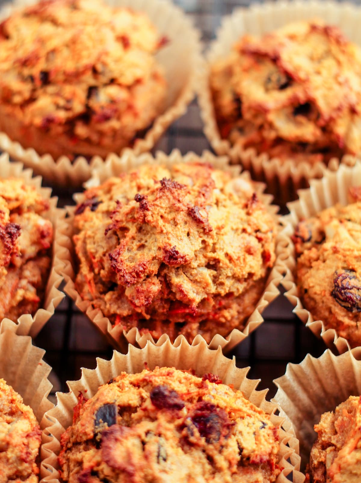 A batch of coconut flour muffins with carrots and raisins cooling on a rack.