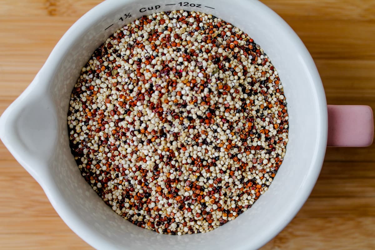 A measuring cup of dry tri-colored quinoa.