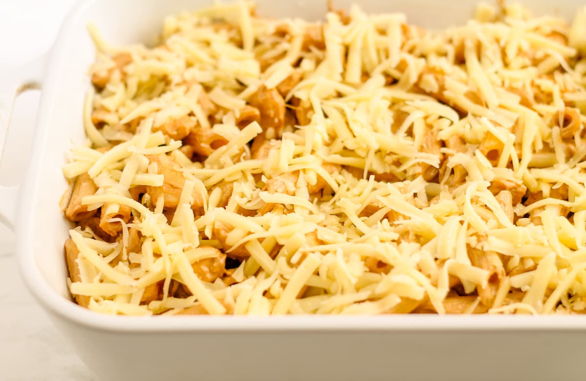 Shredded cheese on top of the ingredients in a casserole dish.
