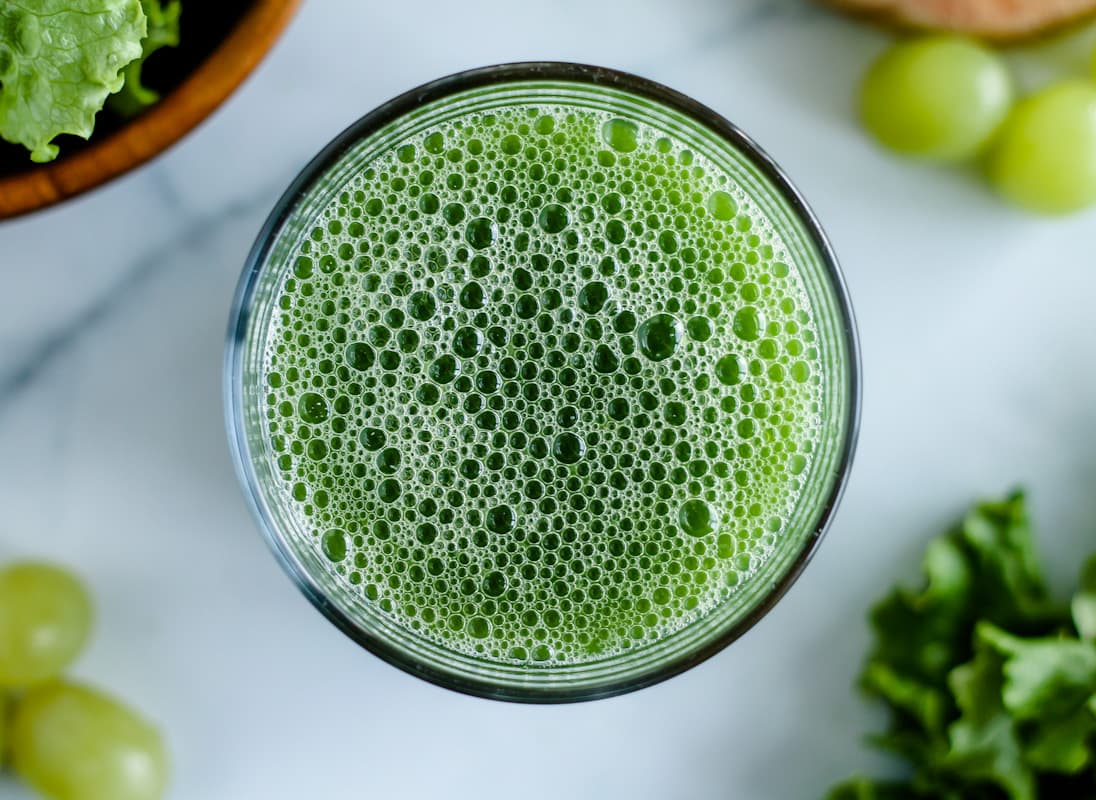 Overhead image of a glass of green juice.