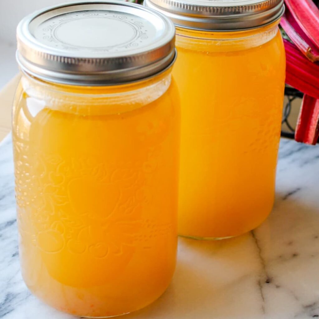 Two jars of homemade vegetable broth on a counter.