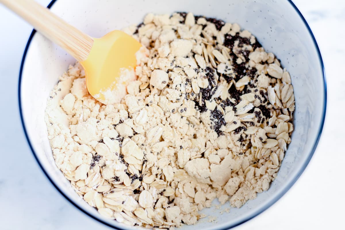 A bowl of dry ingredients being stirred together with a spatula.