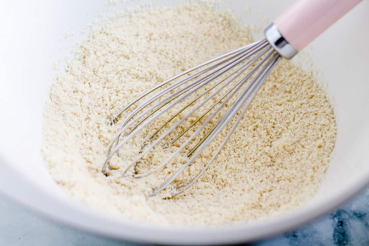 A whisk stirring ingredients in a bowl.