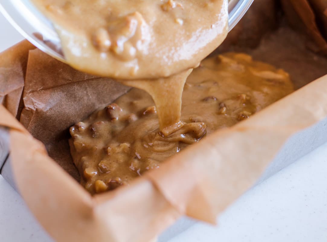 Ingredients being poured into a loaf pan.