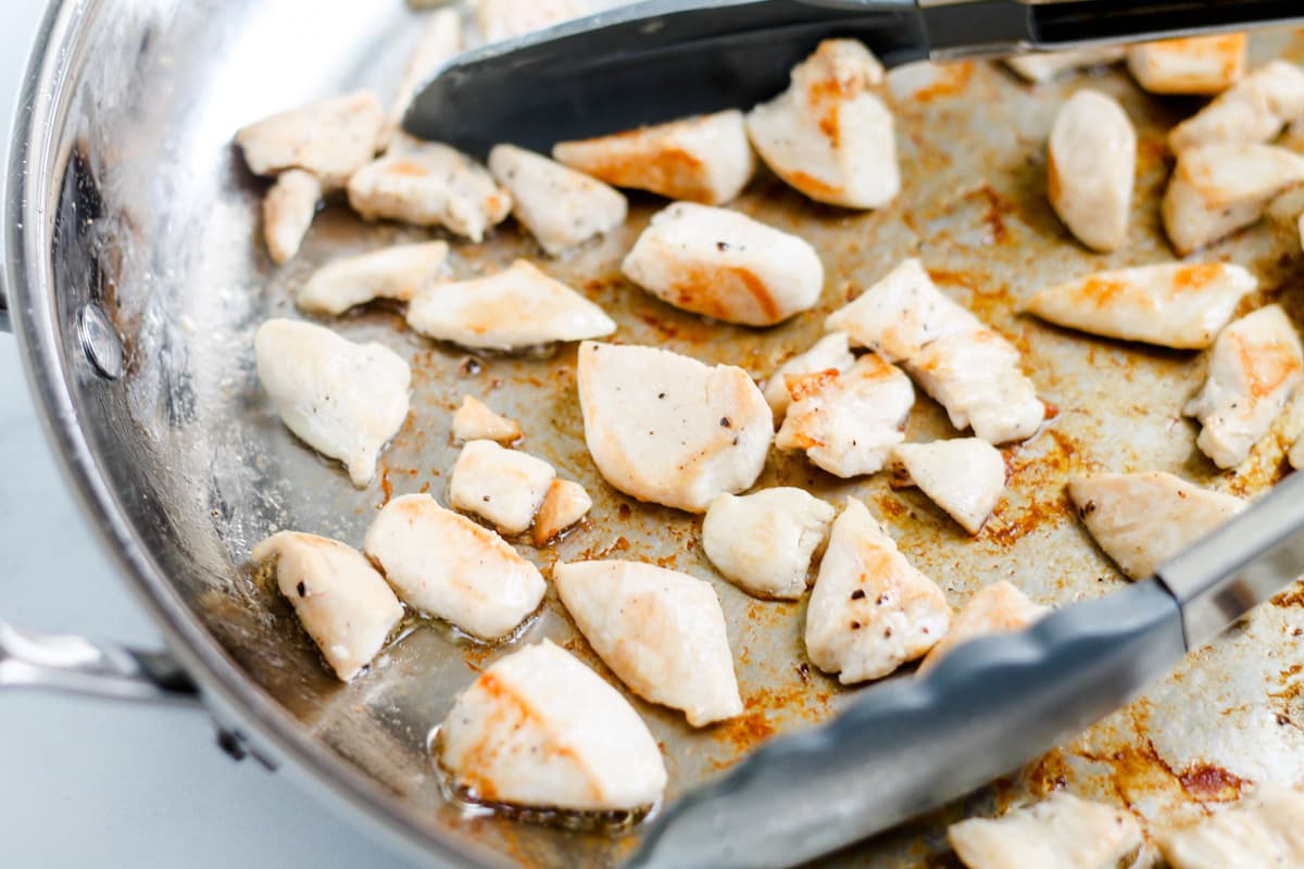 Chicken pieces being cooked in a pan.